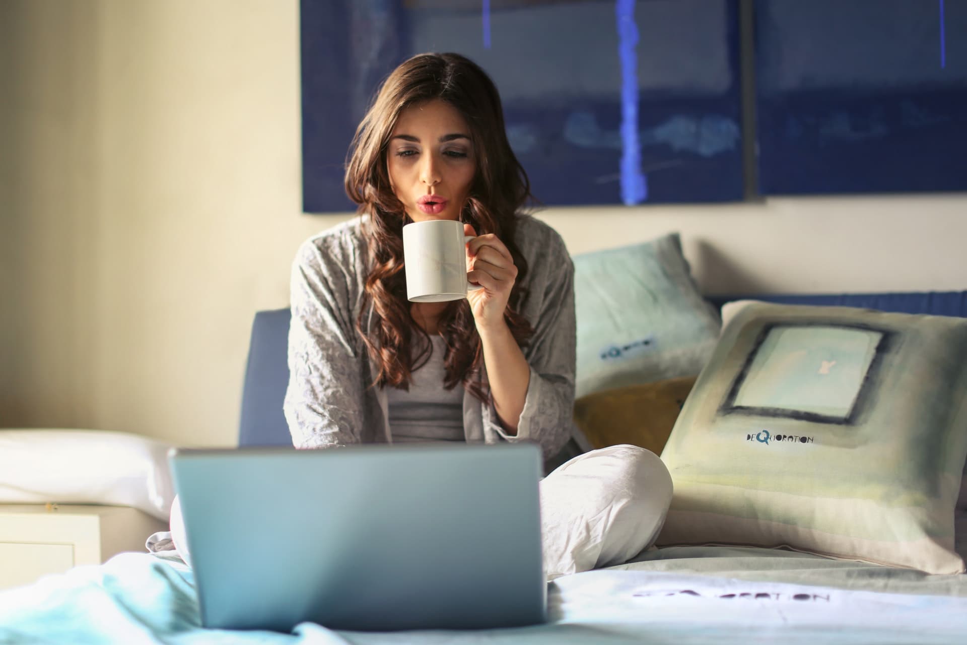 This image shows a woman drinking coffee while looking at her different lending options through our student loan calculator.